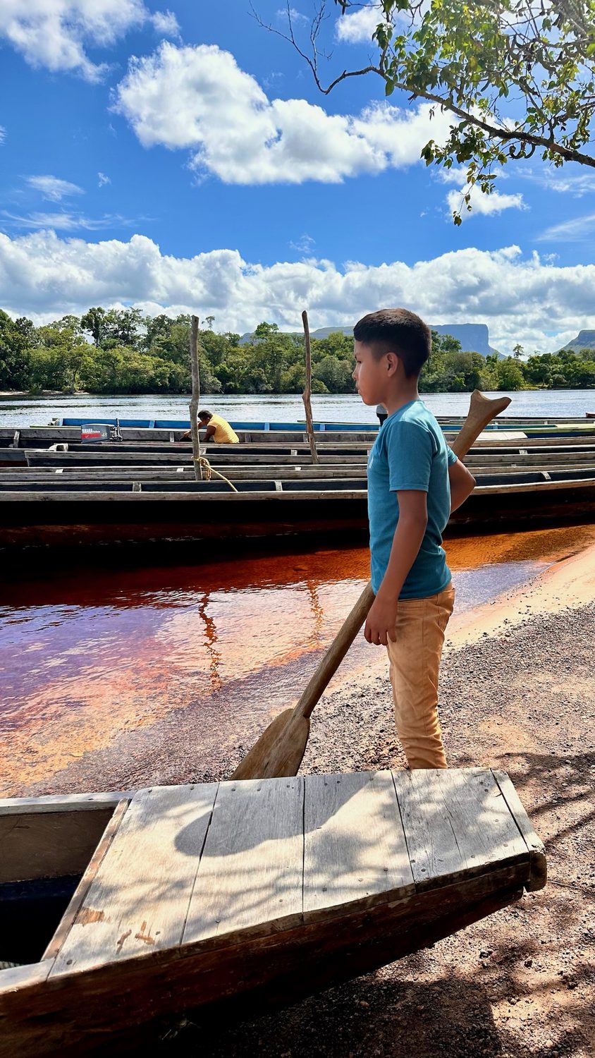 Niño junto a una canoa en el río